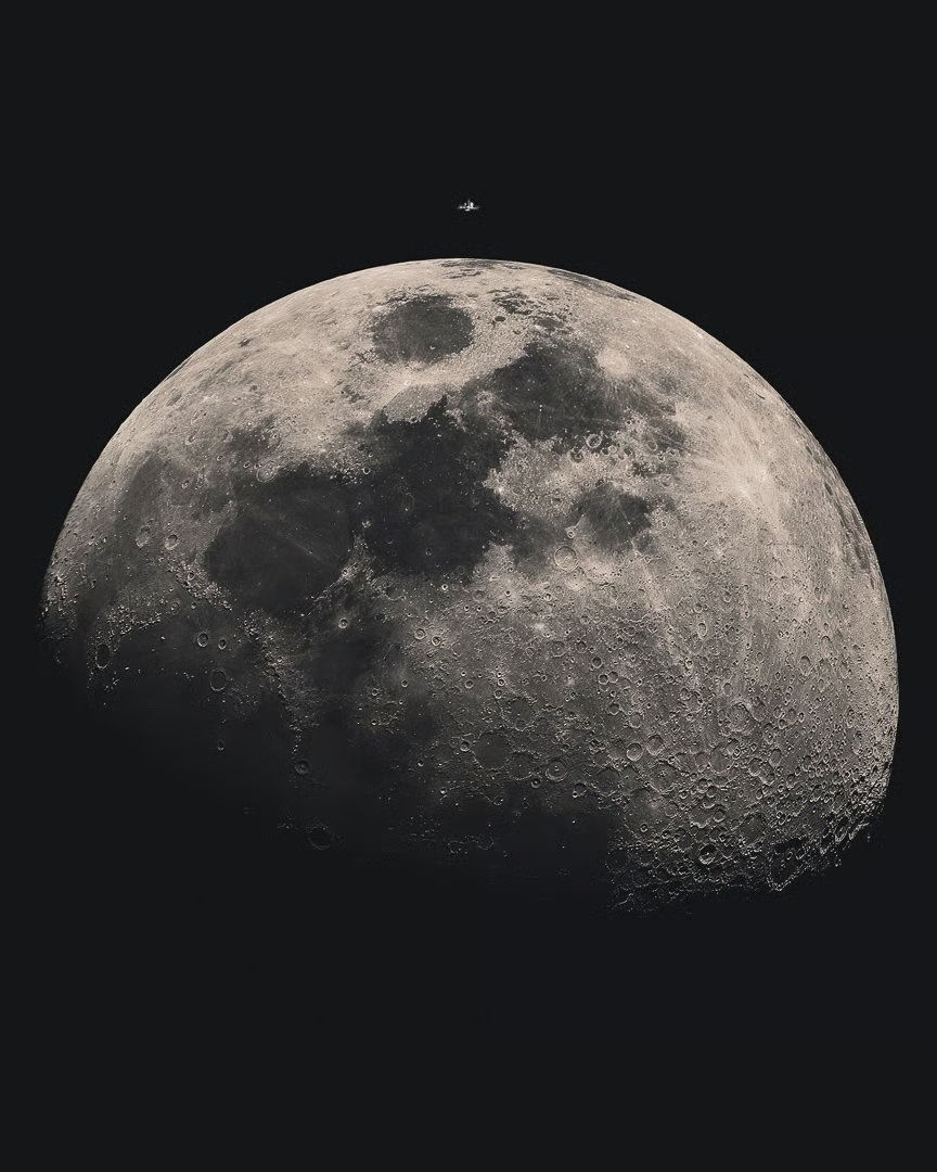 A photo of the International Space Station transiting above the moon